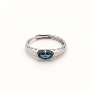 Front view of a marquise london blue topaz ring on a white background, showing the horizontal deep blue-green gemstone, four-prong setting, and overlapping silver-colored band.