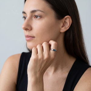 London Blue Topaz ring worn on a hand resting beneath the chin, styled with a black sleeveless top.