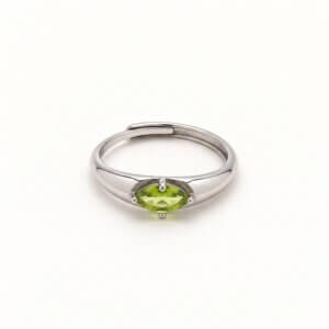 Front view of a marquise peridot ring on a white background, showing the horizontal yellow-green gemstone, four-prong setting, and overlapping silver-colored band.