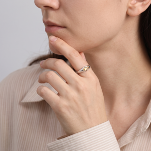 East-west citrine ring worn on a finger resting against the chin, styled with a light striped shirt.